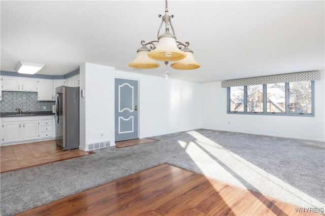 interior space with sink, white cabinetry, tasteful backsplash, light carpet, and stainless steel refrigerator