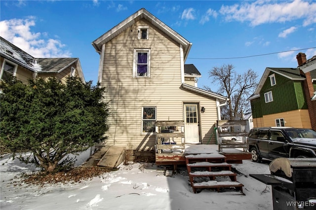 snow covered back of property featuring a wooden deck