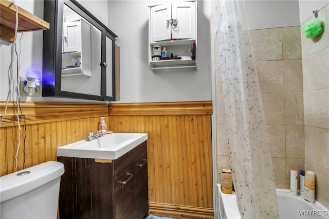 full bathroom featuring shower / tub combo with curtain, vanity, toilet, and wood walls