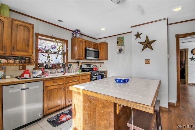 kitchen featuring stainless steel appliances, ornamental molding, a center island, and tile counters