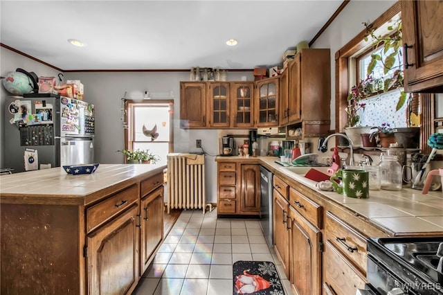 kitchen with radiator, light tile patterned floors, sink, stainless steel appliances, and tile counters