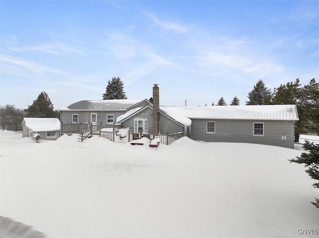 snow covered back of property featuring a wooden deck