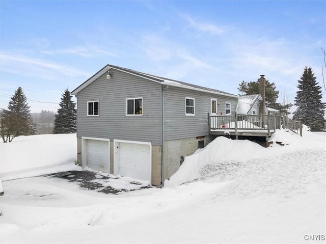 snow covered house with a wooden deck and a garage