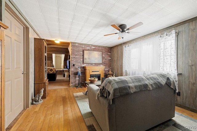 living room featuring ceiling fan, wooden walls, and light wood-type flooring