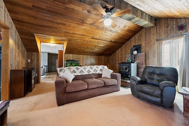 carpeted living room featuring wood walls, wood ceiling, vaulted ceiling, a wood stove, and ceiling fan