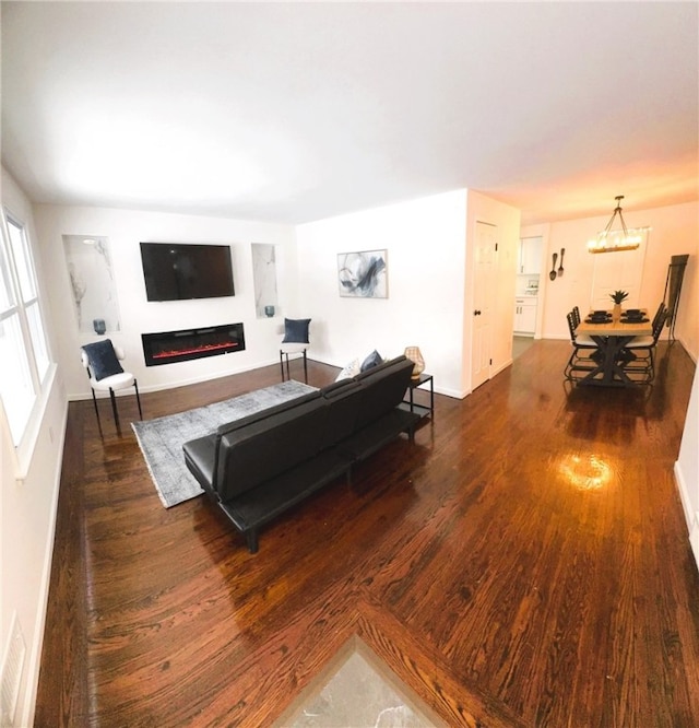 living room featuring an inviting chandelier and dark hardwood / wood-style floors