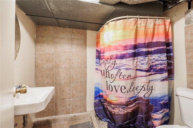 bathroom with a drop ceiling, curtained shower, and toilet