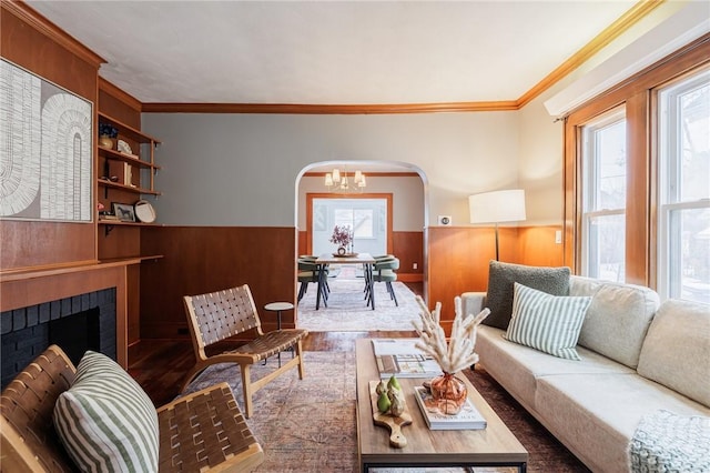 living room with an inviting chandelier, a brick fireplace, hardwood / wood-style floors, and a healthy amount of sunlight