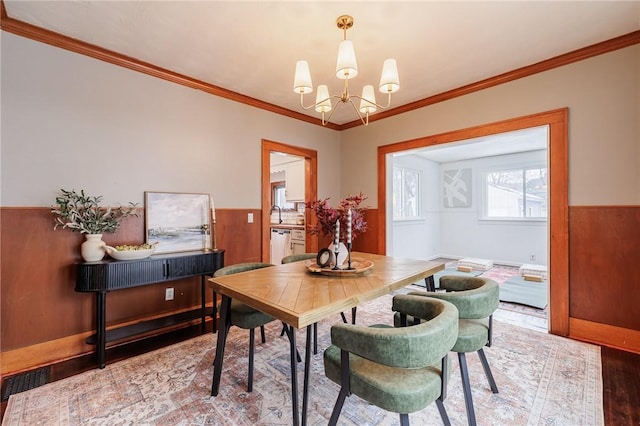 dining area featuring an inviting chandelier, ornamental molding, hardwood / wood-style floors, and wood walls