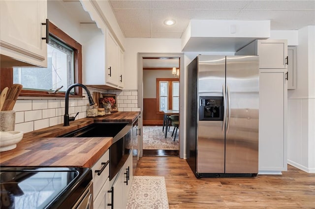 kitchen featuring butcher block counters, white cabinetry, light hardwood / wood-style floors, and stainless steel refrigerator with ice dispenser