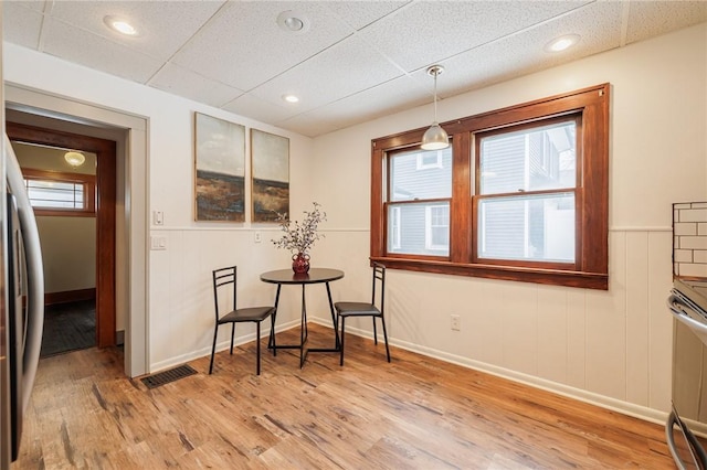 dining space featuring light hardwood / wood-style flooring and a drop ceiling