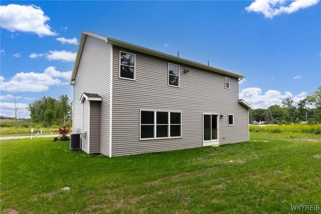 rear view of house featuring central AC unit and a lawn