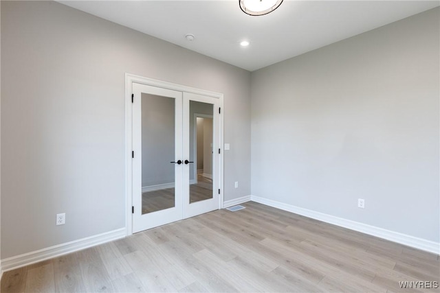 spare room with light hardwood / wood-style floors and french doors