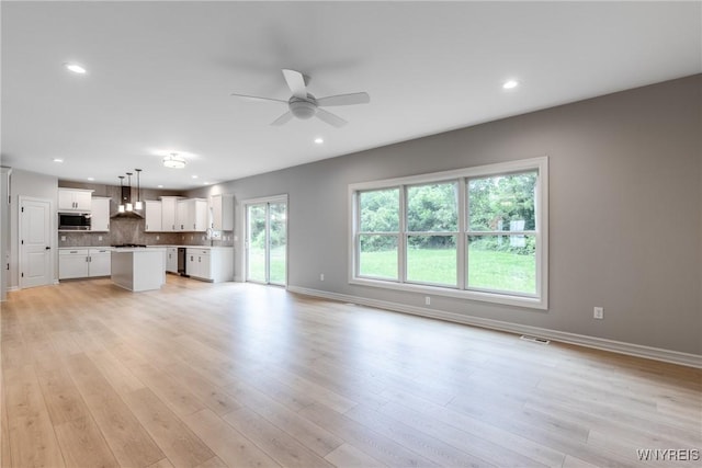 unfurnished living room featuring ceiling fan and light hardwood / wood-style flooring