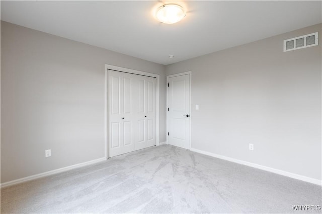 unfurnished bedroom with light colored carpet and a closet