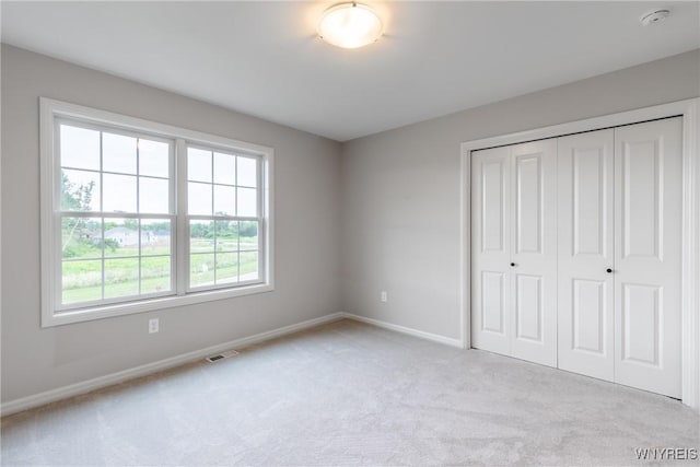 unfurnished bedroom featuring light colored carpet and a closet