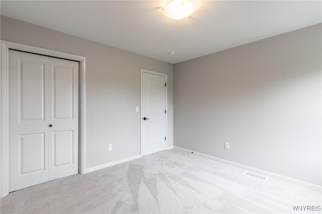 unfurnished bedroom with light carpet and a closet