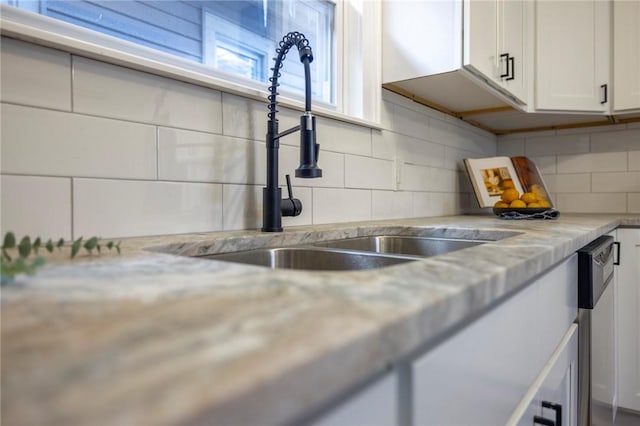 room details featuring light stone counters, sink, backsplash, and white cabinets