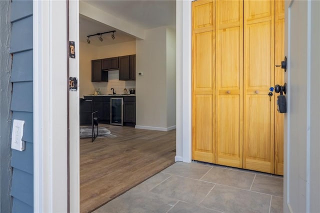 interior space with wine cooler, light tile patterned floors, sink, and rail lighting