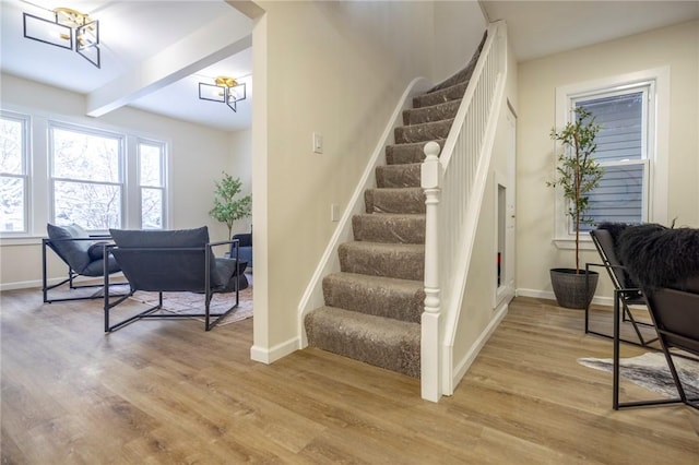 stairs featuring beam ceiling and wood-type flooring