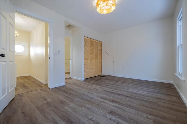 unfurnished bedroom featuring multiple windows, wood-type flooring, and a closet