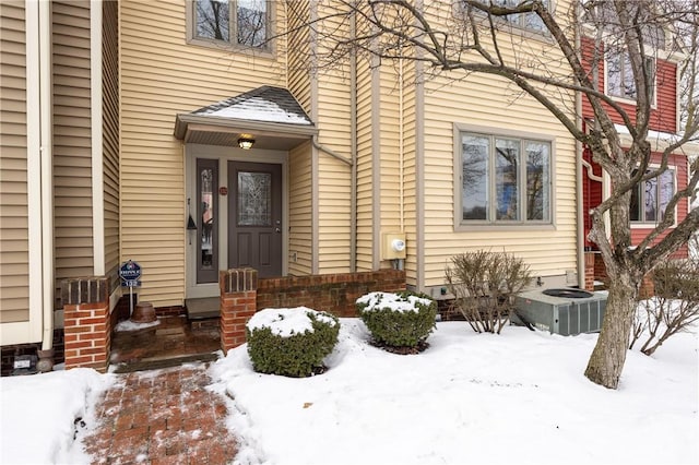 snow covered property entrance with central air condition unit