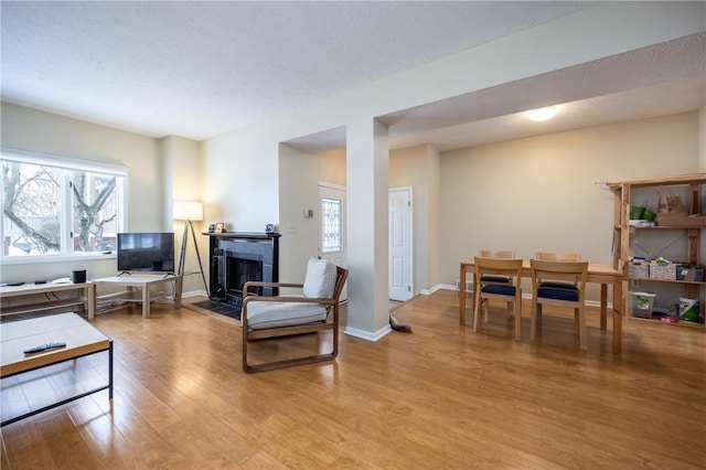 living room with a tile fireplace, a textured ceiling, and light hardwood / wood-style flooring