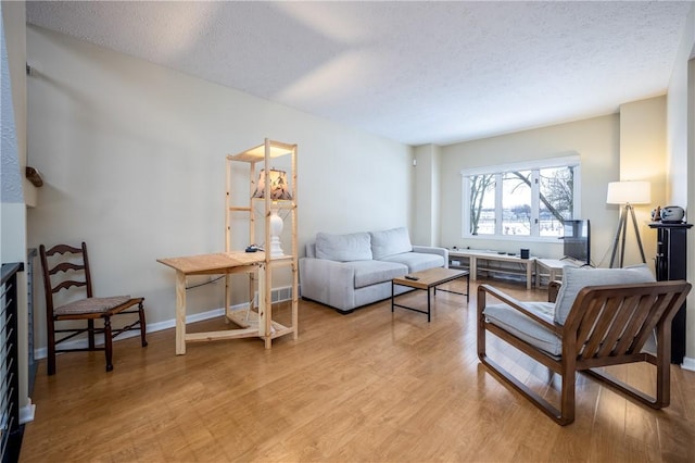 living room featuring light hardwood / wood-style flooring and a textured ceiling