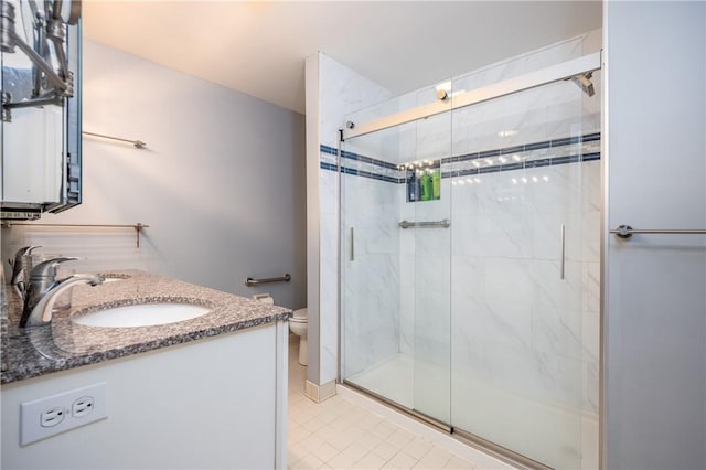 bathroom with toilet, vanity, and a shower with shower door