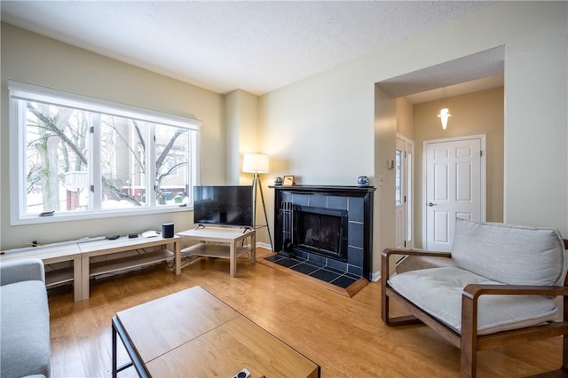 sitting room with hardwood / wood-style flooring, a tiled fireplace, and a textured ceiling