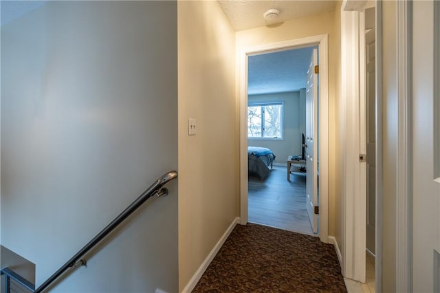 hallway with light colored carpet and a textured ceiling