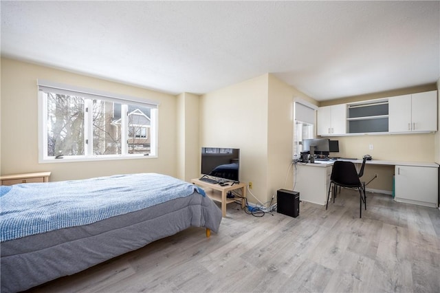 bedroom with built in desk and light wood-type flooring