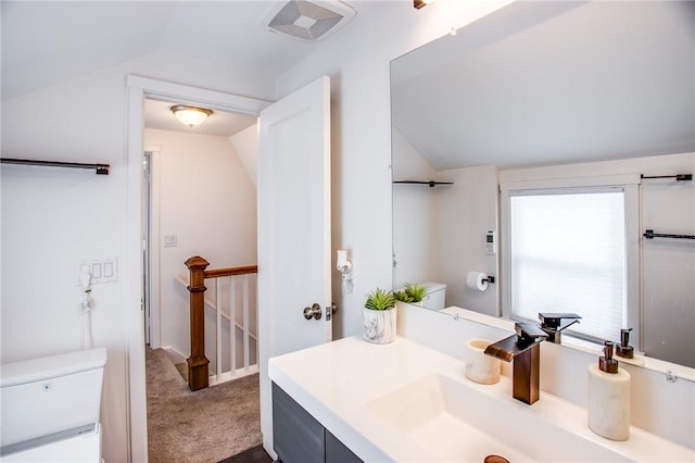 bathroom featuring vanity, lofted ceiling, and toilet