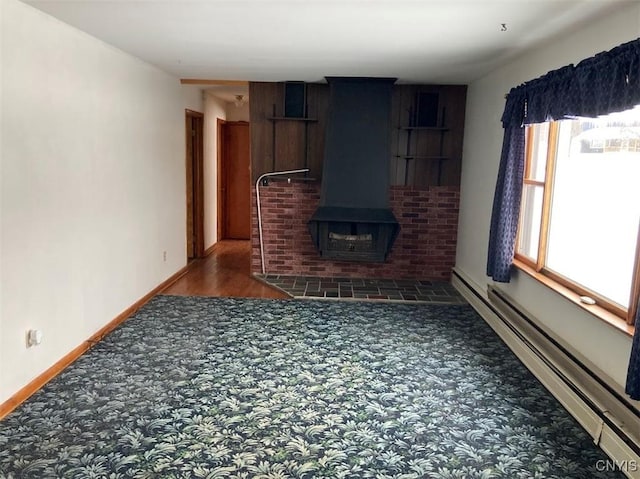 unfurnished living room featuring dark carpet, a wood stove, and a baseboard heating unit