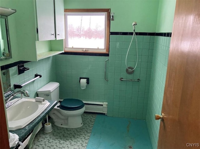 bathroom featuring tile walls, a baseboard heating unit, sink, and toilet