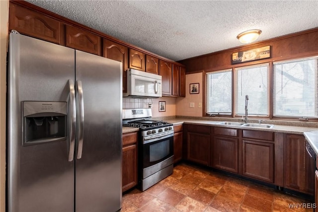 kitchen featuring decorative backsplash, appliances with stainless steel finishes, sink, and a textured ceiling