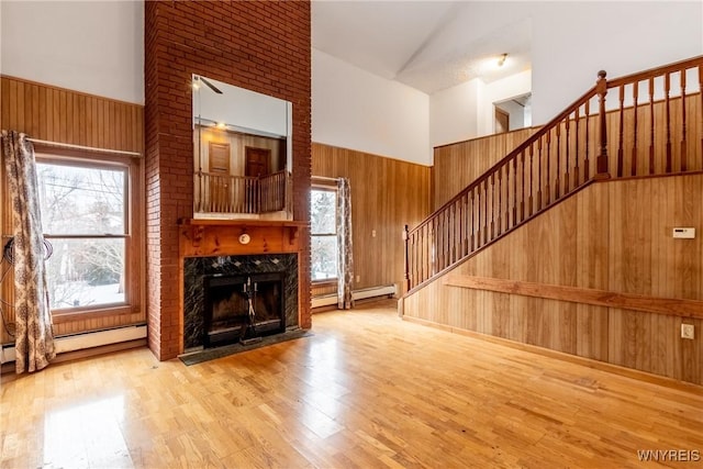 unfurnished living room with wood-type flooring, a high end fireplace, wooden walls, and a healthy amount of sunlight