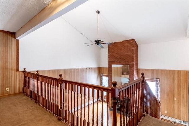 hall with a baseboard radiator, carpet floors, and wooden walls