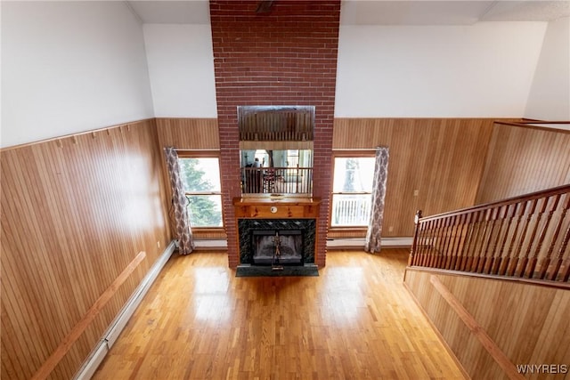 unfurnished living room with a large fireplace, hardwood / wood-style floors, and wood walls