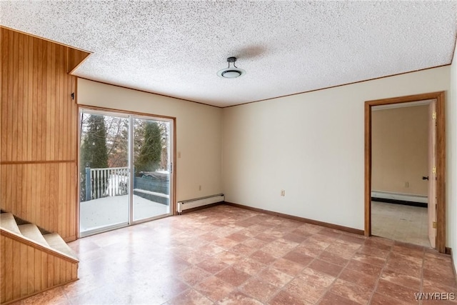 spare room with wood walls, a textured ceiling, and a baseboard heating unit