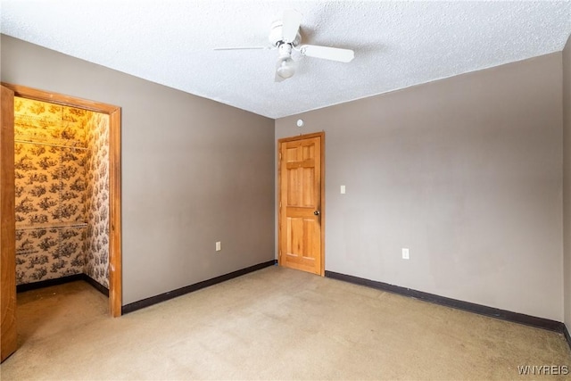 empty room featuring ceiling fan, light colored carpet, and a textured ceiling