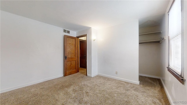 unfurnished bedroom with light carpet and a closet