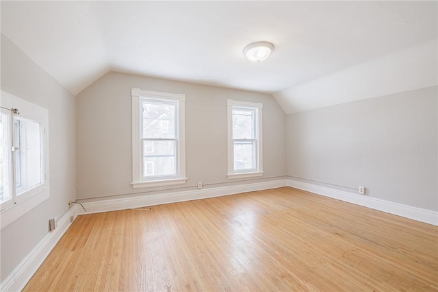 additional living space with light hardwood / wood-style floors and vaulted ceiling