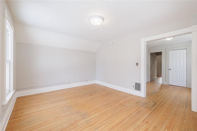 additional living space featuring vaulted ceiling and light wood-type flooring