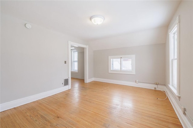 empty room with plenty of natural light and light hardwood / wood-style floors