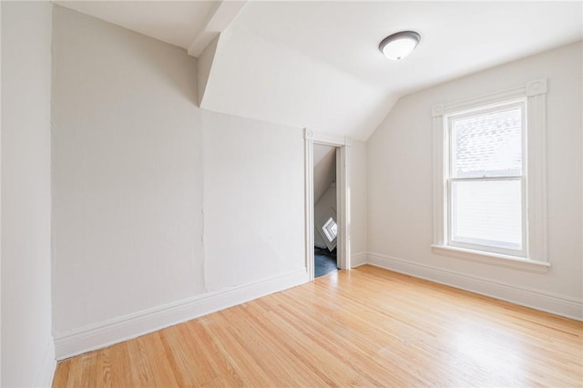 additional living space with hardwood / wood-style flooring and vaulted ceiling