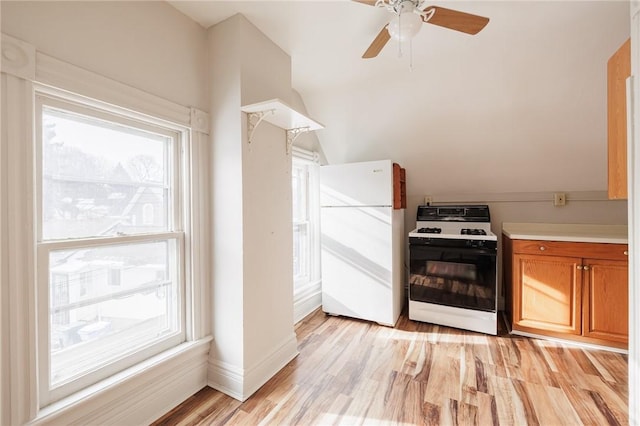 kitchen featuring lofted ceiling, white fridge, ceiling fan, light hardwood / wood-style floors, and gas range