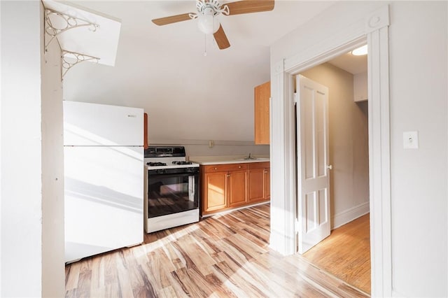 kitchen with sink, gas range, white fridge, ceiling fan, and light hardwood / wood-style floors