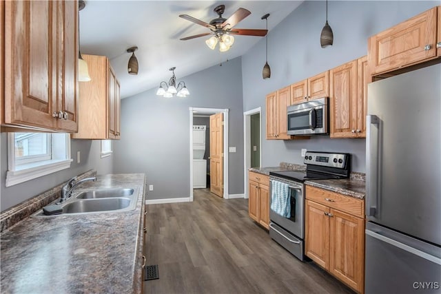 kitchen featuring stainless steel appliances, dark wood-type flooring, stacked washer / dryer, pendant lighting, and sink