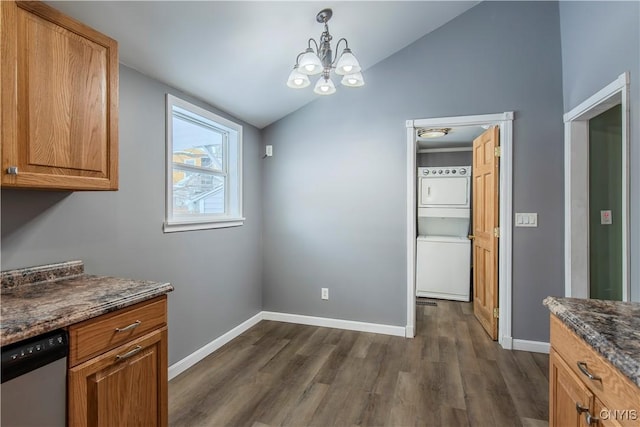 unfurnished dining area featuring dark wood-type flooring, stacked washer / dryer, an inviting chandelier, decorative light fixtures, and vaulted ceiling